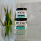 Two jars of 'Don't Be Jelly' moisturizer placed on a surface with a blurred background, one jar is labeled as 2oz and the other as 4oz.