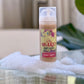 A pump bottle of Rose Quartz Creamy Facial Cleanser with a visible label and a pink-colored liquid, placed on a reflective surface with bubbles around it,