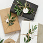 Three different styles of gift wrapping with natural materials such as twine and leaves, tied around a gift box.