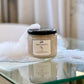 A clear jar of homemade sugar scrub on a bathroom counter, with a label that reads 'Sugar Scrub 12 oz'. 