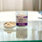 A jar of Camouflage, Calming facial cleanser and mask, placed on a reflective surface.