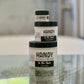 Three jars of Handy Hand Cream labeled 'IN THE NUDE'  placed on a reflective surface with natural lighting.