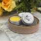 solid perfume tins displayed with one open to show a light yellow color and smooth balm. 