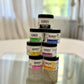 Handy Lotion Collection 4 oz Gift Set  in these scents: Petal Meadow, Joyful, Nude, High Pine, Sauna Rescue, Signature Spa, and Lavender Plains (1x EACH,&nbsp;4 oz) stacked. on blured backround 