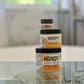 3 jars of diffrent sizes labeled handy simply joyful on a glass table
