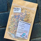 A craft zip bag labeled 'Facial Steam Inhalent' with various dried herbs visible through the clear packaging, placed on a dark, textured surface.
