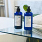 Two blue pump bottles of shampoo on a glass surface.