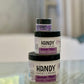 3 jars of handy cream with purple labels in a glass table 