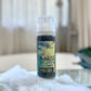 A pump bottle of Smoky Quartz Creamy Facial Cleanser on a bathroom countertop with a white spongy substance next to it, 