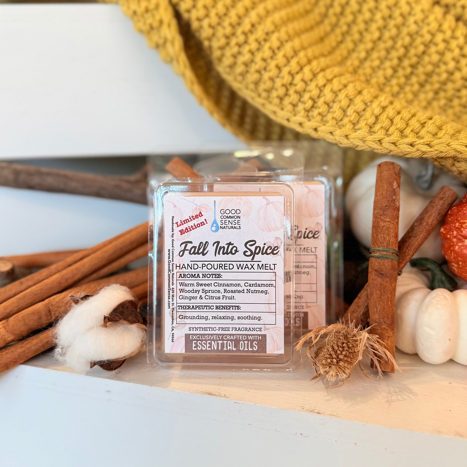 Fall Into Spice hand-poured wax melt displayed with cinnamon sticks, mini pumpkins, cotton, and a cozy mustard knit blanket.