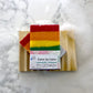rainbow colored bar of soap named love is love on a wooden soap dish 