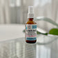 brown spray bottle labeled, Blown Away, Blow Dry Spray. on glass table 