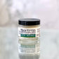 A jar of Tough Titties Soothing Nipple Balm with labels indicating it is a moisturizing and soothing product for nipples, made with organic ingredients.