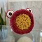 red headband with eyeballs on top wrapped around a large sea sponge. 