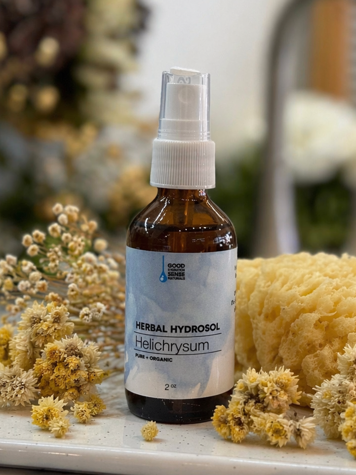 Herbal helichrysum hydrosol bottle with flowers and a sponge on a marble surface