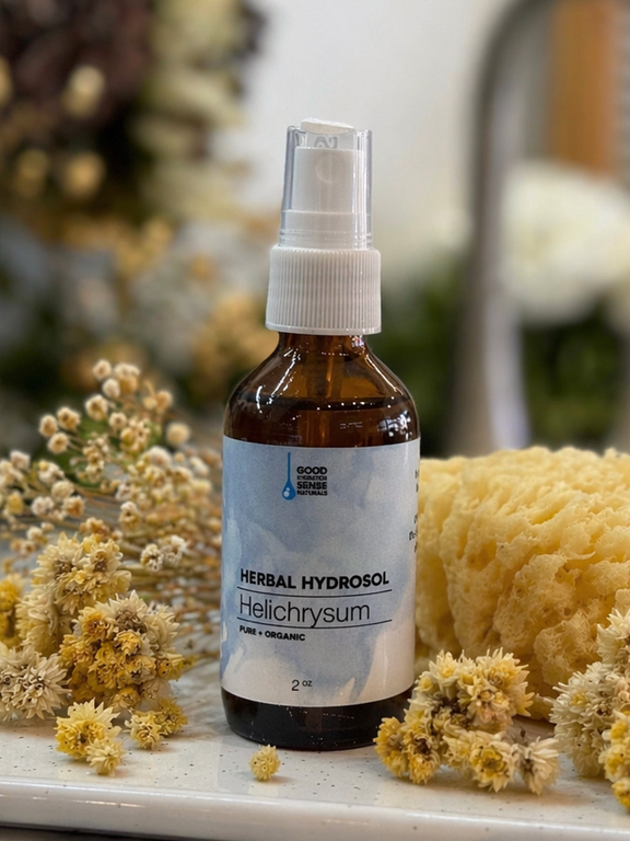 Herbal helichrysum hydrosol bottle with flowers and a sponge on a marble surface
