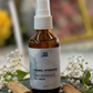 Sandalwood hydrosol bottle on a decorative tray with sandalwood sticks and flowers.
