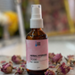 Herbal rose hydrosol bottle with dried roses on a marble surface