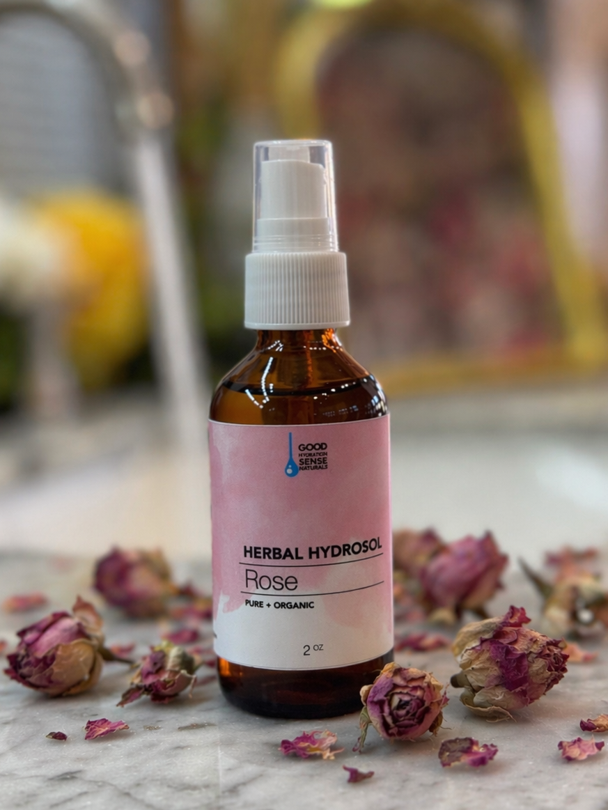 Herbal rose hydrosol bottle with dried roses on a marble surface
