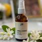 Bottle of Herbal Hydrosol Neroli on a marble surface with flowers