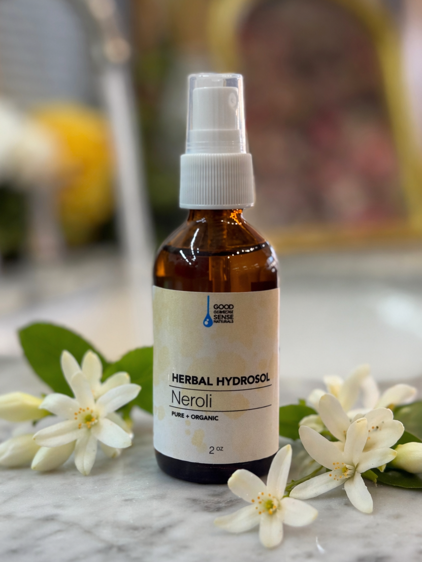 Bottle of Herbal Hydrosol Neroli on a marble surface with flowers