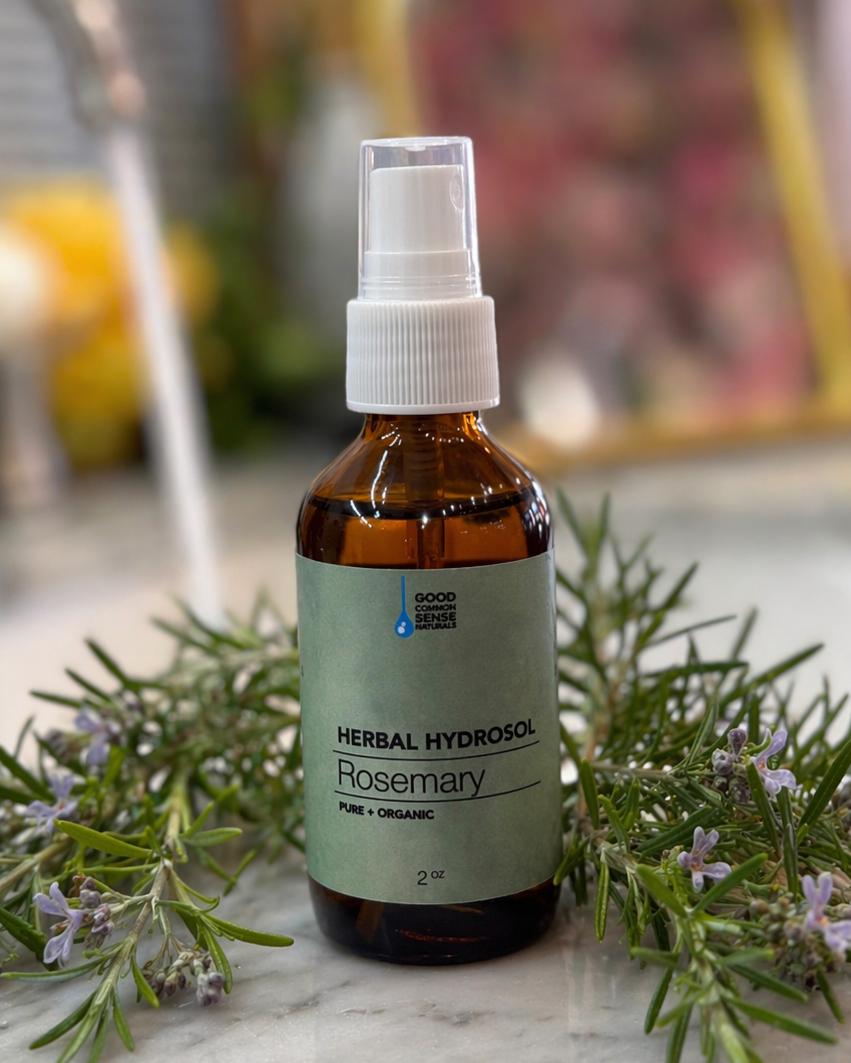 Bottle of herbal hydrosol with rosemary on a marble surface
