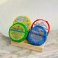 A collection of shower steam tablets with different colored wrappers displayed on a wooden stand.