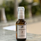 A bottle of Botanical Beard Oil with a white spray nozzle, placed on a marble surface.