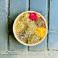 woode bowl filled with Detox Herbal Bath Ingredients: Rose, Calendula, Yarrow, Lavender, Rosemary, Comfrey, Thyme, Holy Basil. on a blured backround 
