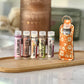 A set of  lip balms in a variety of flavors, displayed in a row on a wooden tray, with an orange lip balm holder in the center.