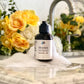 A bottle of Obsidian African Black Soap Cleanser on a marble surface with a flower arrangement in the background and a tap in the foreground.