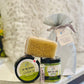 A gift set from Restoration Hardware, including a jar labeled 'Oh my Buttah', another jar marked 'Buff My Soul', a body dry brush, and a small tube of lip balm, all displayed on a counter.