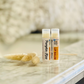 two lip balms standing together namesd pumpkin kiss on marbeld surface 