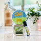A gift set containing a blue bath bomb with green lettering, a clear roller bottle with gold lettering, and a green lotion bar with gold lettering, displayed on a marble surface with plants in the background.