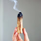hand holding a burning Palo Santo stick 