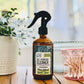 brown spray bottle labeled all pourpose cleaner on wooden table with plant in background