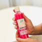 A pink bottle of Bubbles Up! Petal Meadow body wash being held by a person with the label clearly showing the product name 
