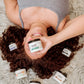 girl laying on ground with all handy creams surrounding her on a carpet  