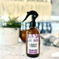 A spray bottle labeled 'Lounge Peaceful' with a purple and white label design, displayed on a kitchen countertop.