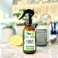 A bottle of Lounge Sauna Rescue room and linen spray with eucalyptus & bergamot scents, displayed on a marble surface with a plant and decorative items in the background.