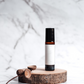 Aromatherapy roller bottle with a white label on a wooden stand, with marble background.