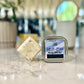 salveation massage lotion bar tin with the bar next to it with blurred background 