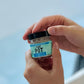 hands holding a jar labeled that pot vitimin E balm 