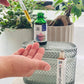 A person holding a dropper bottle of Tranquility Sensitive Face Serum, with a plant background and another bottle of the serum visible in the foreground.