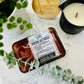 A package of 'Sauna Retreat' wax melts by Good Sense, with a candle and plant decor in the background.