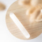 A smooth, white selenite wand placed on a wooden surface.