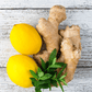 A photo showing lemon and ginger root on a white wooden background, which are part of the Focus Essential Oil Blend.