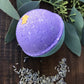 purple bath bomb with blue bottom with leafs in background 