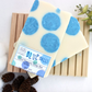 a white bar of soap with blue circles all around set on a wood soap saver 