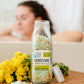 glass jar filled with green bath salts labeled Herbivore on a wood table 